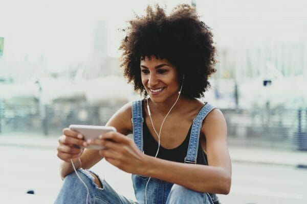 Image of a woman watching something on her phone with headphones on
